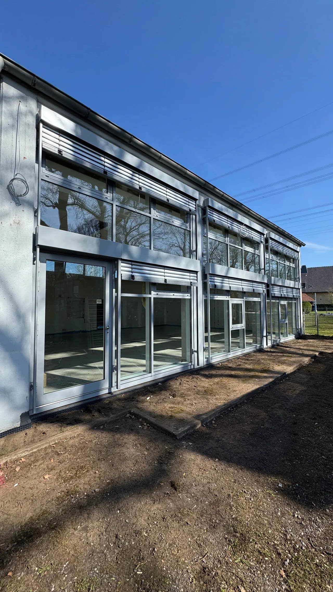 Moderne Gebäudefassade mit Raffstoren an den Fenstern im Obergeschoss und Glastüren im Erdgeschoss