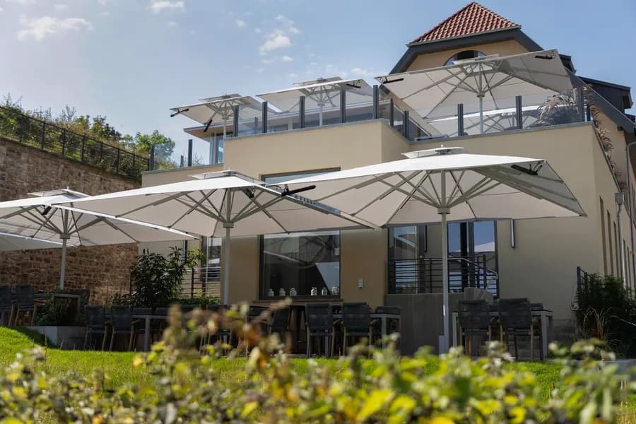 Mehrere große weiße Sonnenschirme vor einem Restaurantgebäude