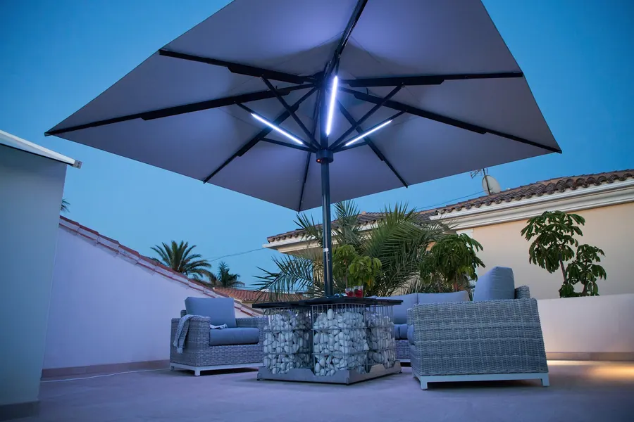 Beleuchteter Sonnenschirm über einer Lounge in der Abenddämmerung