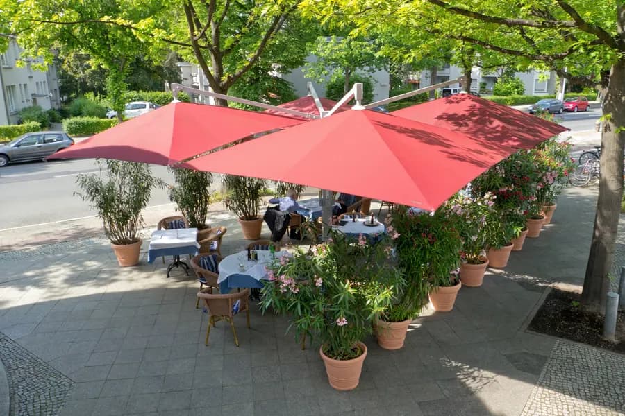 Rote Sonnenschirme über den Tischen einer Café-Terrasse